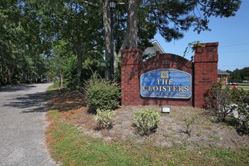 Myrtle Beach apartment for rent - The entrance to The Cloisters with a blue sign on a brick wall.