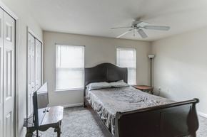 Sandersville apartment for rent - A bedroom with a bed, a chair, and a ceiling fan.