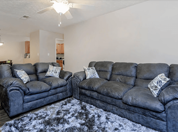 Newnan apartment for rent - Two grey leather sofas with pillows in a living room.