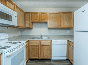 Newnan apartment for rent - A kitchen with wooden cabinets and a white stove top oven.