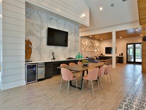 Austin apartment for rent - A clubhouse with a community meeting table, charis, a wet bar, and a TV near a lounge area with comfortable seating.