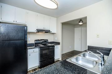 Bay Point apartment for rent - A black fridge sits in a kitchen with white cabinets and a black counter top.