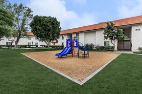Palm Springs apartment for rent - A playground with a blue slide in front of a white building with the number 511 on it.