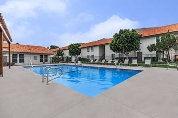 Palm Springs apartment for rent - A swimming pool in front of a building with a red roof.