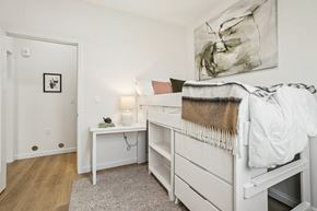 Los Angeles apartment for rent - A bedroom with a white bed and a white nightstand with a lamp on it.