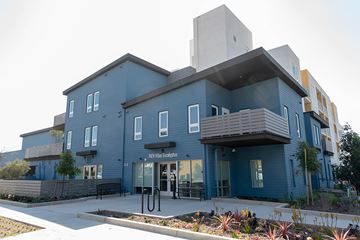 Inglewood apartment for rent - A modern building with a blue facade and a sign that reads "Pinyon Village Schools".