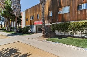 Winnetka apartment for rent - A building with a red awning is surrounded by trees and shrubs.