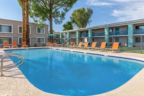 Phoenix apartment for rent - A swimming pool with orange lounge chairs and a building in the background.