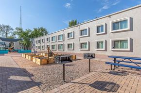 Phoenix apartment for rent - A building with a white exterior and multiple windows is surrounded by a gravel area with benches and a speaker.