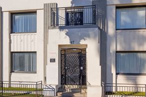 Long Beach apartment for rent - A white building with a black gate and a sign that says 87.