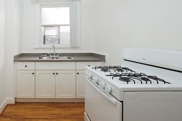 Long Beach apartment for rent - A white gas stove in a kitchen with wooden floors and white cabinets.