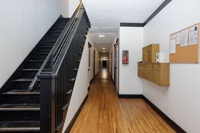 Long Beach apartment for rent - A long hallway with a staircase on the left and a bulletin board on the right.