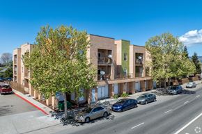 Oakland apartment for rent - A street view of a multi-story building with cars parked in front.