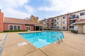 Sacramento apartment for rent - A swimming pool in a residential area with a building in the background.