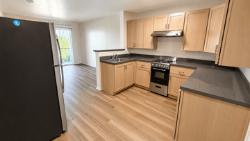 Buena Park apartment for rent - A kitchen with wooden cabinets and a black fridge.