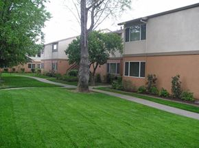 Sacramento apartment for rent - an apartment building with a green lawn and sidewalk