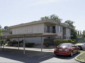 Fairfield apartment for rent - A red car is parked in a parking lot in front of a building.