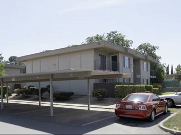 Fairfield apartment for rent - A red car is parked in a parking lot in front of a building.