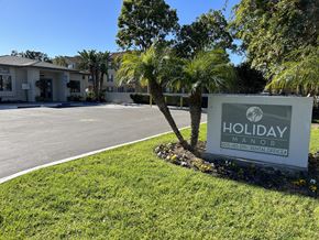 Oxnard apartment for rent - a sign that says holiday manor in front of a palm tree