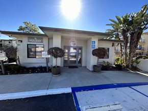 Oxnard apartment for rent - the front entrance of a building with a driveway and palm trees