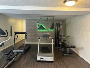 Reseda apartment for rent - a gym with a treadmill and weights in a room with a wall with a sign