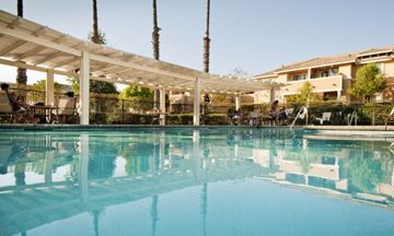 Jurupa Valley apartment for rent - A large outdoor swimming pool with people relaxing on the sun loungers.