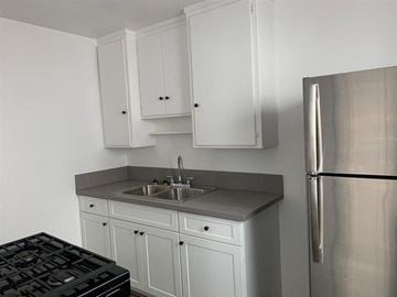 Long Beach apartment for rent - a kitchen with white cabinets and a stainless steel refrigerator
