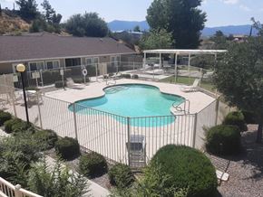 Globe apartment for rent - a pool with a fence around it and a house in the background