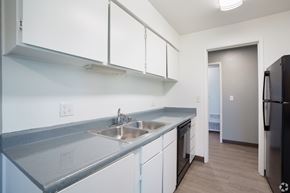Pittsburg apartment for rent - A kitchen with white cabinets and a black fridge.