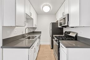 Monrovia apartment for rent - A kitchen with white cabinets and a black stove top oven.