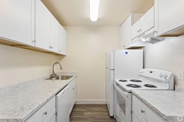 San Jose apartment for rent - A kitchen with white cabinets and a white stove top oven.
