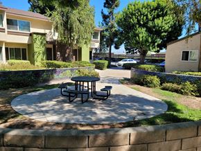 Santa Ana apartment for rent - a patio with a table and benches in front of a building