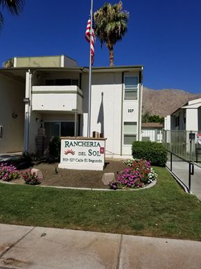 Palm Springs apartment for rent - a building with a sign and a palm tree in front of it