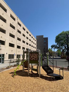 Santa Rosa apartment for rent - A playground with a slide and a climbing frame in front of a building.