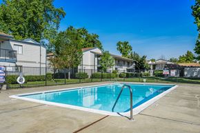 Sacramento apartment for rent - A swimming pool in a residential area surrounded by houses and trees.