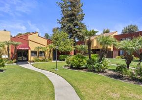 West Covina apartment for rent - a sidewalk in front of a building with palm trees at Brookhollow Apartments, California