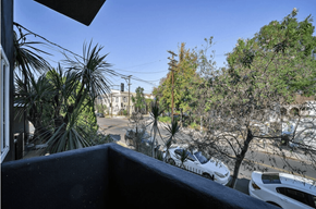 Los Angeles apartment for rent - A view from a balcony overlooking a parking lot and trees.