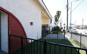 Van Nuys apartment for rent - A white house with a red arched doorway and a black fence.