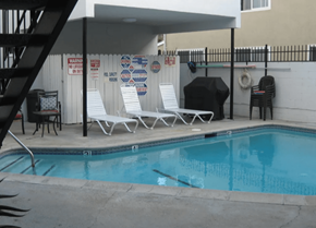 Burbank apartment for rent - A pool with a black umbrella and white chairs.