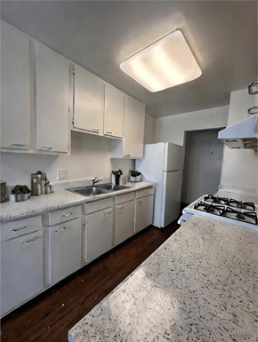 San Pedro apartment for rent - A kitchen with white cabinets and a granite countertop.