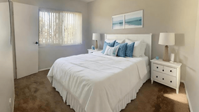 San Pedro apartment for rent - A bedroom with a large bed, a nightstand, and a window with curtains.