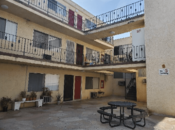 Van Nuys apartment for rent - A patio with a table and chairs is surrounded by apartment buildings.