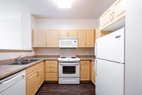 Pomona apartment for rent - a kitchen with white appliances and wooden cabinets