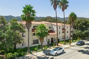Verdugo City apartment for rent - A white car is parked on the street in front of a building with a red tile roof.