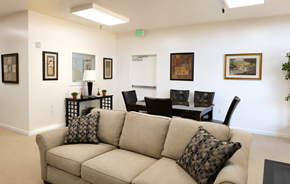 Redding apartment for rent - A beige couch with two pillows sits in a room with a white wall and a painting hanging on it.