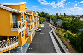 Redding apartment for rent - A white car is parked on the street in front of a yellow building.