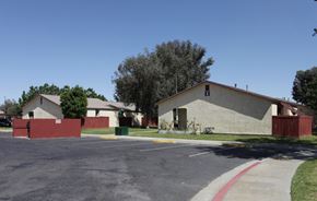 Coachella apartment for rent - a white house with a red fence and a street