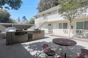 San Jose apartment for rent - A patio with a table and chairs is in front of a white building.