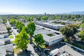 San Jose apartment for rent - A view of a residential area with houses, trees, and a parking lot.