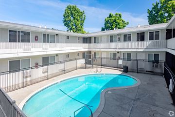 San Jose apartment for rent - A swimming pool in a courtyard surrounded by a fence.